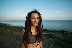 Ragazza scompigliata con i dreadlocks su una montagna che trascura il mare fotografia stock libera da diritti Ragazza scompigliata con i dreadlocks su una montagna che trascura il mare fotografia stock libera da diritti