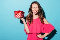 Ragazza sorridente felice in vestito che tiene scatola attuale e sbattere le palpebre Immagini Stock Ragazza sorridente felice in vestito che tiene scatola attuale e sbattere le palpebre Immagini Stock