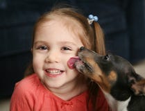 Ragazza sveglia che è leccata da un cane immagine stock Ragazza sveglia che è leccata da un cane immagine stock