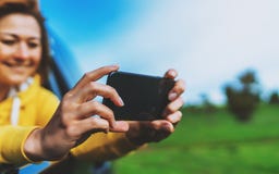 Ragazza turistica di sorriso in una finestra aperta di un'automobile automatica che prende il selfie della foto sullo Smart Phone immagini stock Ragazza turistica di sorriso in una finestra aperta di un'automobile automatica che prende il selfie della foto sullo Smart Phone immagini stock