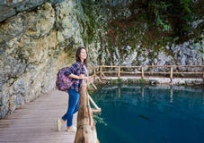 Ragazza turistica sorridente graziosa esile con la condizione dello zaino sulla via di legno immagini stock libere da diritti Ragazza turistica sorridente graziosa esile con la condizione dello zaino sulla via di legno immagini stock libere da diritti