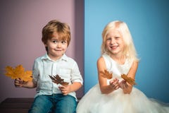 Ragazzino e ragazza in vestiti stagionali con la foglia dorata Piccoli bambini felici che giocano con le foglie e che esaminano immagine stock Ragazzino e ragazza in vestiti stagionali con la foglia dorata Piccoli bambini felici che giocano con le foglie e che esaminano immagine stock