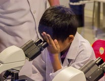 Ragazzo asiatico che guarda tramite il microscopio fotografia stock Ragazzo asiatico che guarda tramite il microscopio fotografia stock