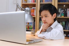 Ragazzo asiatico che lavora al computer fotografie stock Ragazzo asiatico che lavora al computer fotografie stock