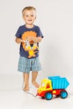 Ragazzo biondo che gioca con la piccola automobile di plastica fotografia stock libera da diritti Ragazzo biondo che gioca con la piccola automobile di plastica fotografia stock libera da diritti