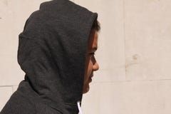 Ragazzo di scuola disturbato triste dell'adolescente con il cappuccio sulla posa del diritto all'aperto da solo davanti alla pare fotografie stock libere da diritti Ragazzo di scuola disturbato triste dell'adolescente con il cappuccio sulla posa del diritto all'aperto da solo davanti alla pare fotografie stock libere da diritti