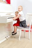 Ragazzo e ragazza che giocano sul piano bianco fotografia stock libera da diritti Ragazzo e ragazza che giocano sul piano bianco fotografia stock libera da diritti