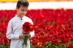 Ragazzo sveglio con un mazzo dei ranuncoli nella primavera fotografia stock Ragazzo sveglio con un mazzo dei ranuncoli nella primavera fotografia stock