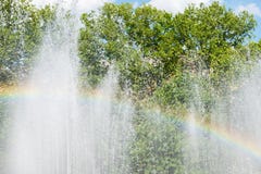 Rainbow over water in fountain with green trees on background. Defocused Royalty Free Stock Photos Rainbow over water in fountain with green trees on background. Defocused Royalty Free Stock Photos