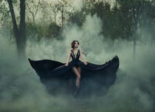 A rainha escura, com pés longos desencapados, anda névoa Um vestido preto luxuoso alarga-se em sentidos diferentes, como as asas fotos de stock A rainha escura, com pés longos desencapados, anda névoa Um vestido preto luxuoso alarga-se em sentidos diferentes, como as asas fotos de stock