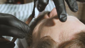 Rasage du processus des barbes dans le raseur-coiffeur Le maître fait un client de barbe de coupe de cheveux avec le rasoir droit banque de vidéos Rasage du processus des barbes dans le raseur-coiffeur Le maître fait un client de barbe de coupe de cheveux avec le rasoir droit banque de vidéos