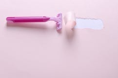 Razor for woman on the pink background.Sharp and safe shaving.Torn paper after using blade stock image Razor for woman on the pink background.Sharp and safe shaving.Torn paper after using blade stock image