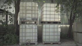 Reagent liquid storage tanks standing outdoors in sunlight. Containers for chemical substances on concrete mixes