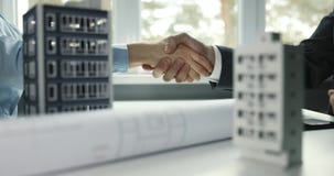Real estate development - businessmen handshake in office after successful agreement of commercial and apartment building