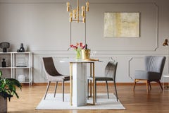 Elegant dining room interior with golden accents, table, chairs and painting on a wall stock photo Elegant dining room interior with golden accents, table, chairs and painting on a wall stock photo