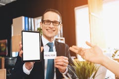 Realtor sitting at desk in office. Realtor is holding tablet, father is pointing at it. royalty free stock photos Realtor sitting at desk in office. Realtor is holding tablet, father is pointing at it. royalty free stock photos