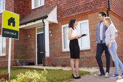 Realtor έξω από το σπίτι για την πώληση με το νέο ζεύγος στοκ εικόνα Realtor έξω από το σπίτι για την πώληση με το νέο ζεύγος στοκ εικόνα