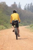 Rear view of bicycle man riding on dirt road with drinking water royalty free stock image Rear view of bicycle man riding on dirt road with drinking water royalty free stock image