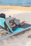 Rear view of freelance businesswoman using laptop on the beach stock photography Rear view of freelance businesswoman using laptop on the beach stock photography