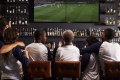 Rear View Of Friends Watching Game In Sports Bar Celebrating stock photo Rear View Of Friends Watching Game In Sports Bar Celebrating stock photo