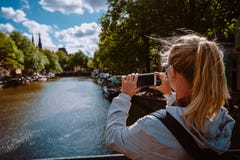 Rear View Of Female Tourist Taking Photo Of Canal In Amsterdam On The Mobile Phone On Sunny Autumn Day. Warm Gold Royalty Free Stock Photo Rear View Of Female Tourist Taking Photo Of Canal In Amsterdam On The Mobile Phone On Sunny Autumn Day. Warm Gold Royalty Free Stock Photo