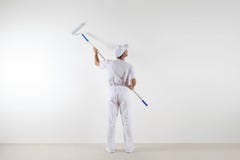 Rear view of painter man looking at blank wall, with paint roller stick, isolated on white room stock images Rear view of painter man looking at blank wall, with paint roller stick, isolated on white room stock images