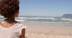 Rear view of young African american woman relaxing on beach in the sunshine 4k stock footage Rear view of young African american woman relaxing on beach in the sunshine 4k stock footage