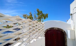 Recinto decorativo del colore bianco contro il cielo blu e la porta luminosa di Borgogna a OIA su Santorini Immagine Stock Recinto decorativo del colore bianco contro il cielo blu e la porta luminosa di Borgogna a OIA su Santorini Immagine Stock