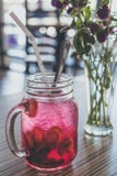 Red Beverage-filled Clear Glass Mason Mug With Straw Beside Purple Flowers in Vase Royalty Free Stock Photo Red Beverage-filled Clear Glass Mason Mug With Straw Beside Purple Flowers in Vase Royalty Free Stock Photo