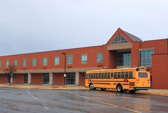 School Building with Bus. Red Brick School Building with Yellow School Bus at the front, ready for transporting students to home or drop off School Building with Bus. Red Brick School Building with Yellow School Bus at the front, ready for transporting students to home or drop off