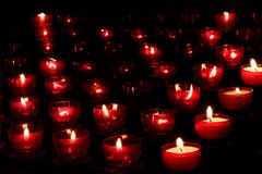 Red candles with glowing lights in darkness in church. Peace and hope background. Religion concept. Stock Photos Red candles with glowing lights in darkness in church. Peace and hope background. Religion concept. Stock Photos