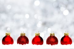 Red Christmas baubles in snow with silver background