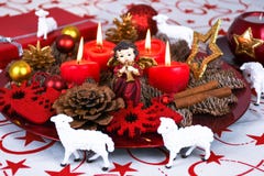 Red Christmas decorated wreath plate with four burning candles on a table cloth surrounded with white sheep stock photos Red Christmas decorated wreath plate with four burning candles on a table cloth surrounded with white sheep stock photos