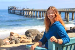 Red-haired happy white Caucasian girl sits on a bench on the shore of the Atlantic Ocean in Swakopmund Namibia and laughs stock photos Red-haired happy white Caucasian girl sits on a bench on the shore of the Atlantic Ocean in Swakopmund Namibia and laughs stock photos