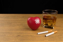 Red heart symbol with adhesive plaster, two cigarettes and a glass of bourbon whiskey royalty free stock photos Red heart symbol with adhesive plaster, two cigarettes and a glass of bourbon whiskey royalty free stock photos