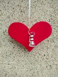 Red heart of wood hanging on a shiny thread on the background of the texture of abstract small stone concrete royalty free stock images Red heart of wood hanging on a shiny thread on the background of the texture of abstract small stone concrete royalty free stock images