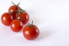 Red juicy cherry tomatoes with green tails lying on a white background stock photos Red juicy cherry tomatoes with green tails lying on a white background stock photos