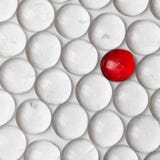 A red marble in a crowd of white marbles