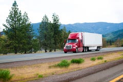 Red modern semi truck with dry van trailer moving by divided hig Stock Images Red modern semi truck with dry van trailer moving by divided hig Stock Images