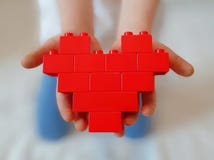 Red toy blocks heart on childs hands. royalty free stock photography Red toy blocks heart on childs hands. royalty free stock photography