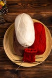 Red and white colored balls of thread and knitting needles with a knitting on a wooden background stock images Red and white colored balls of thread and knitting needles with a knitting on a wooden background stock images