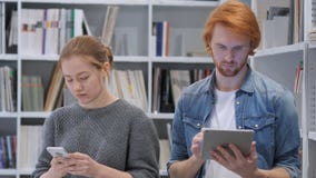 Redhead Man Using Tablet and Woman Using Smartphone in Office royalty free stock photos Redhead Man Using Tablet and Woman Using Smartphone in Office royalty free stock photos