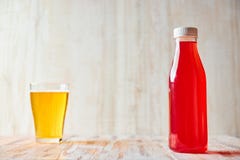 A refreshing berry drink in a plastic bottle with a full glass of light beer in the background. copy space. healthy royalty free stock photo A refreshing berry drink in a plastic bottle with a full glass of light beer in the background. copy space. healthy royalty free stock photo