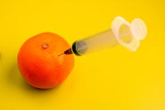 Reife Tangerine mit einer Spritze auf der gelbgrünen Tabelle im Labor r lizenzfreies stockfoto Reife Tangerine mit einer Spritze auf der gelbgrünen Tabelle im Labor r lizenzfreies stockfoto