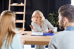 reifen Sie den weiblichen Psychologen, der mit jungen Paaren während der Therapie spricht Lizenzfreie Stockfotos reifen Sie den weiblichen Psychologen, der mit jungen Paaren während der Therapie spricht Lizenzfreie Stockfotos