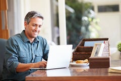 Reifer hispanischer Mann, der zu Hause Laptop auf Schreibtisch verwendet Reifer hispanischer Mann, der zu Hause Laptop auf Schreibtisch verwendet