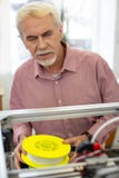 Reizend älterer Mann, der Faden für Drucker 3D hält lizenzfreies stockbild Reizend älterer Mann, der Faden für Drucker 3D hält lizenzfreies stockbild
