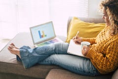 Relaxed adult caucasian woman at work at home with personal laptop computer and notebook - economy and. business alternative