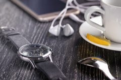 Reloj y teléfono móvil con auriculares y una taza de café en una tabla de madera oscura imagenes de archivo Reloj y teléfono móvil con auriculares y una taza de café en una tabla de madera oscura imagenes de archivo