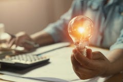 remettez la femme comptable tenant l'ampoule, nouvelle idée avec l'innovati photo libre de droits remettez la femme comptable tenant l'ampoule, nouvelle idée avec l'innovati photo libre de droits